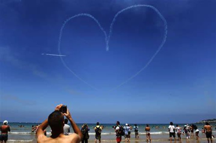Beach goers watch a Spanish Air Force jet fly over a beach in Northern Spain