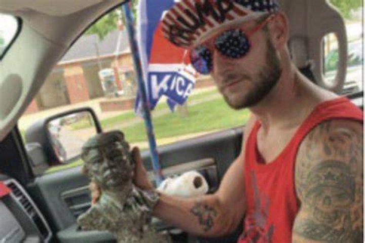 Lance Ligocki holds a statue while sitting in a car.